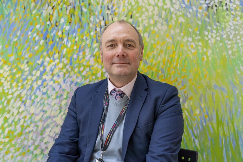 Man in front of painting of flowers